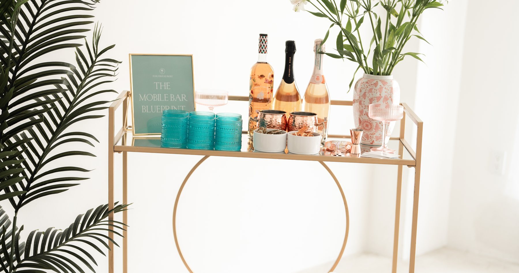 Styled luxury mobile bar cart with The Mobile Bar Blueprint sign, cocktails and florals