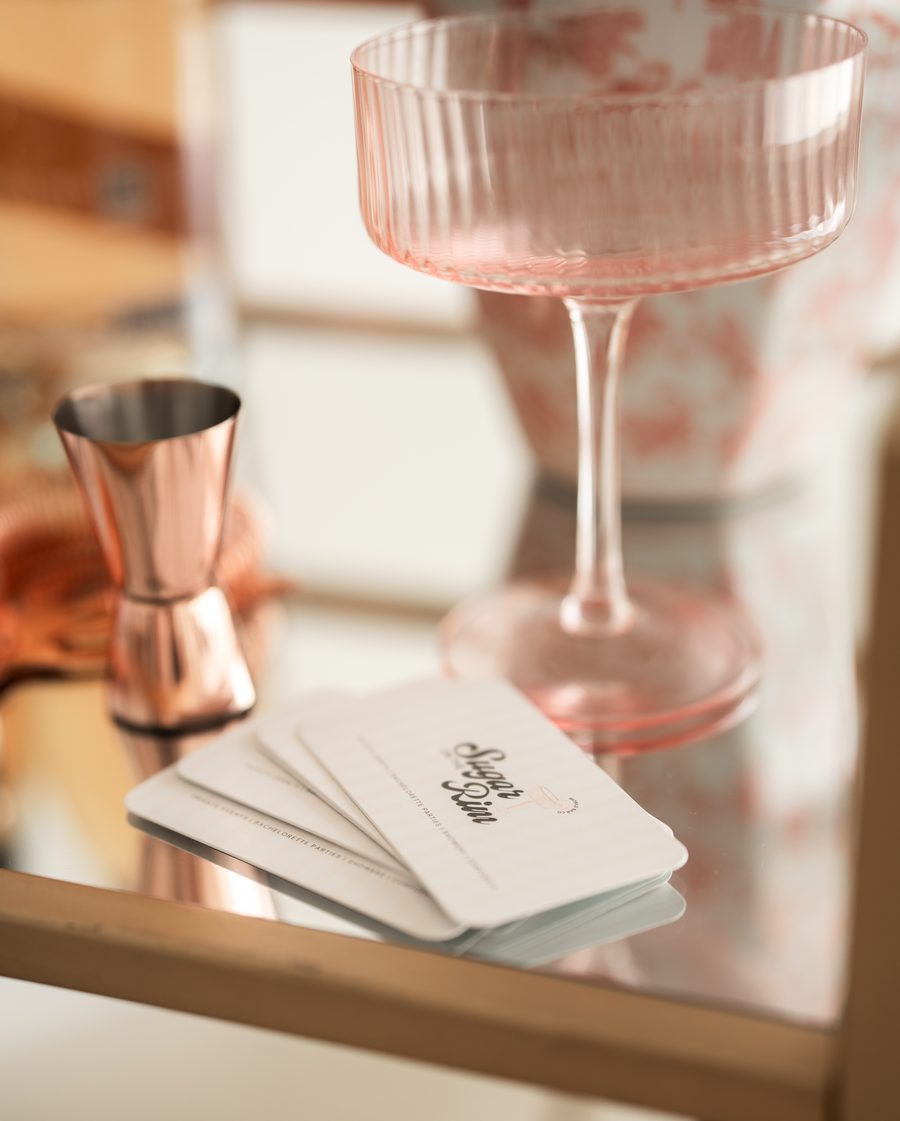 Copper jigger and pink coupe glasses styled on a bar cart